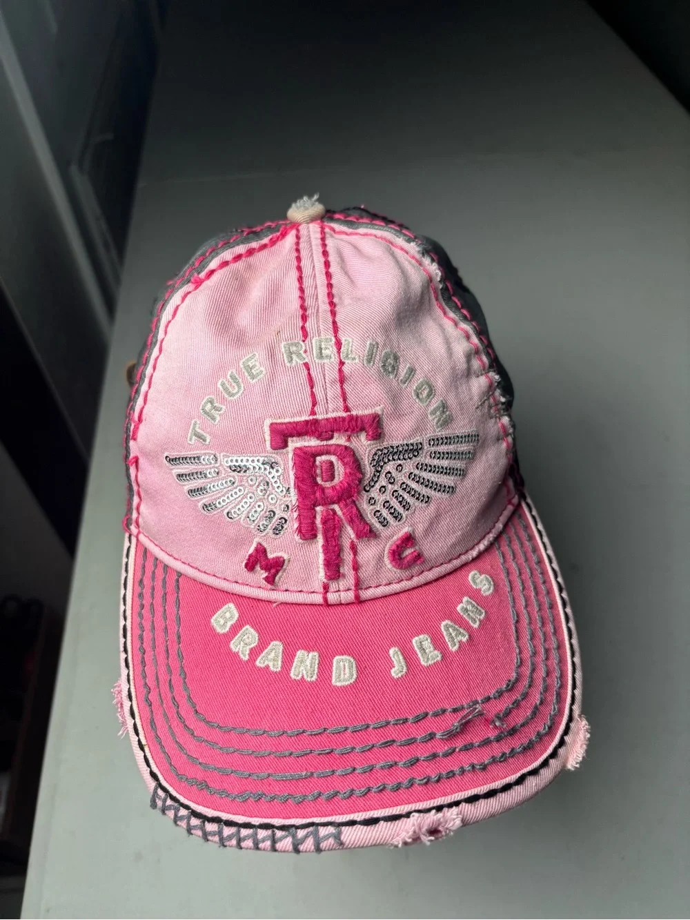 pink, distressed True Religion brand jeans cap with embroidered wings and a logo